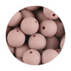 A close-up view of numerous smooth, matte pink silicone round beads for jewelry making.