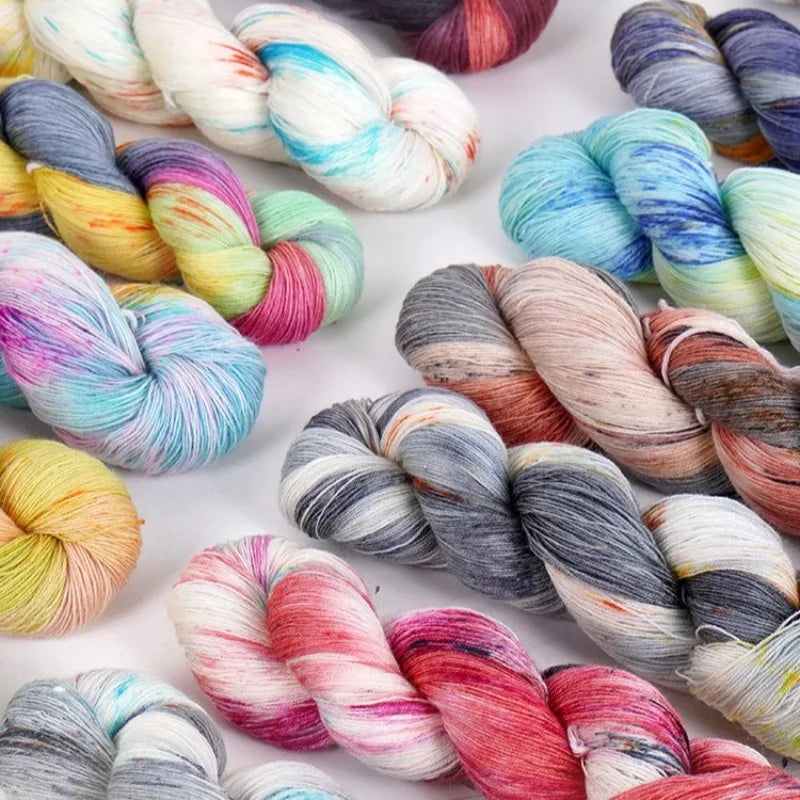 A close-up of hand-dyed Australian wool yarn in various gradient colors, coiled for knitting and crochet.
