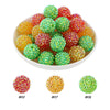 A bowl filled with various colors of green, red, and yellow rhinestone acrylic beads for jewelry making.