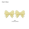 A pair of pale yellow silicone bow tie beads used for jewelry making and craft projects.