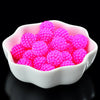 A white bowl filled with bright pink acrylic pearl beads for jewelry making