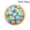 A collection of ten colorful printed silicone beads in various floral patterns arranged on a wooden surface.