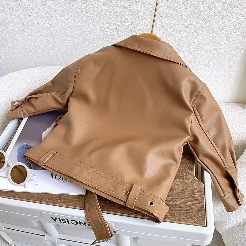 A tan faux leather zip-up jacket is displayed on a white suitcase.