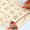 A hand is tracing letters on a wooden Montessori letter tracing board for early learning.