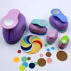 A collection of multi-size paper hole punches in various shades of purple and green, including a pink and blue plastic tool.