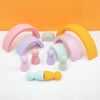 A collection of soft silicone rainbow arch building blocks in pastel colors and various sizes on a white surface.