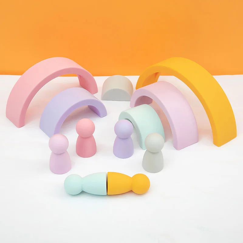 A collection of soft silicone rainbow arch building blocks in pastel colors and various sizes on a white surface.