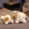 A fluffy white and brown dog plush toy lying on a gray fabric surface.