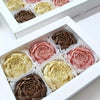 A white box contains silicone molds shaped like roses in various shades of brown, pink, and cream.