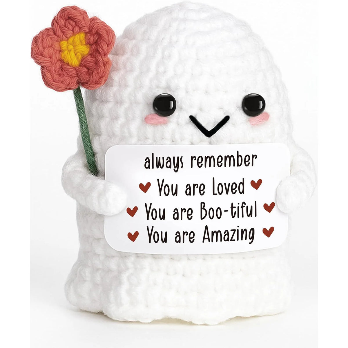 A white crochet ghost doll with a pink flower on its head holding an emotional support card that says You are loved you are b