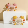 A silicone baby teether shaped like a crab, featuring pink and yellow components.