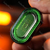 A hand holds a green metal mechanical fidget slider with a diamond pattern design.
