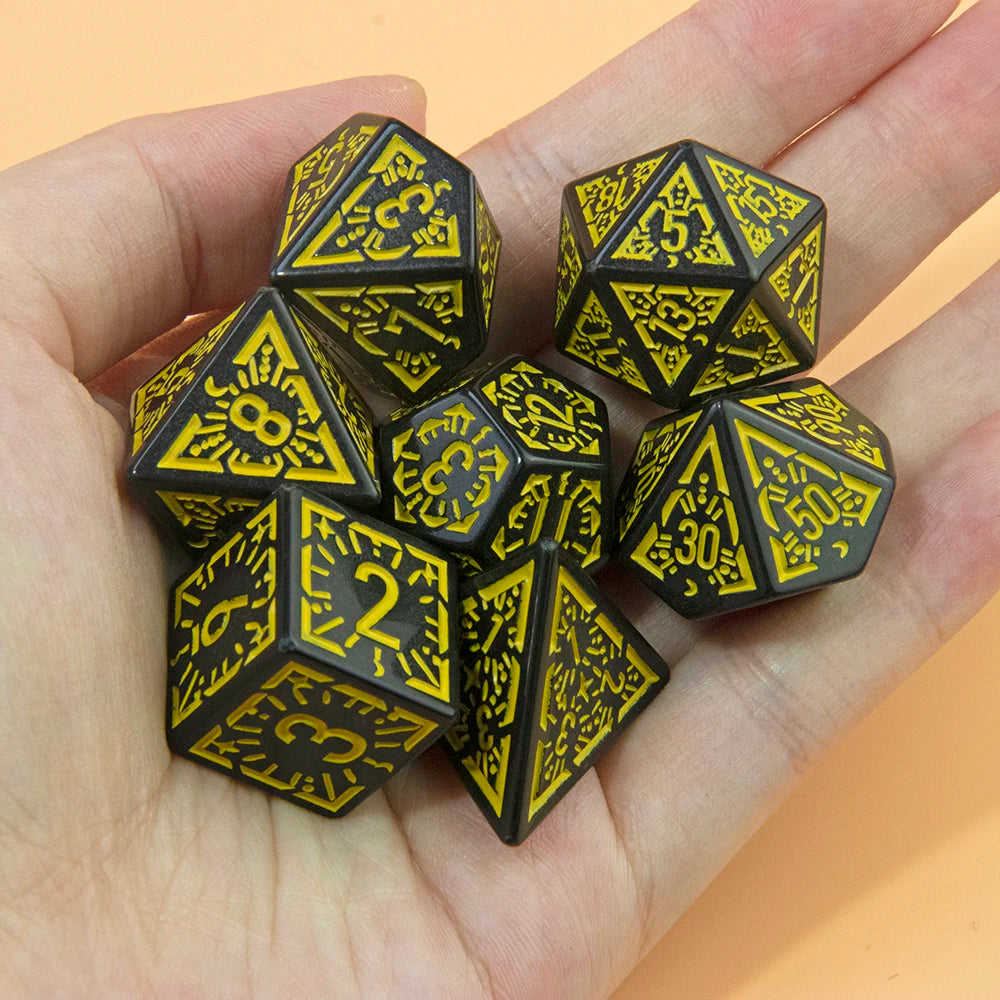 A hand holds a set of black and yellow polyhedral dice used for tabletop games.
