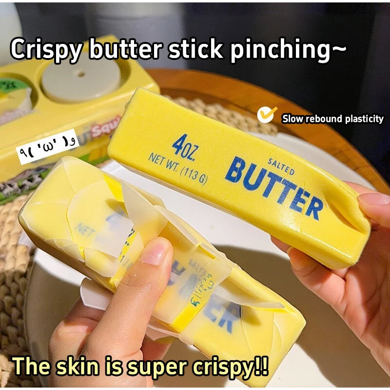 A hand is pinching a yellow butter stick squishy fidget ball, showing its crispy texture.