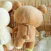 A tan Kawaii Rilakkuma Strawberry Bear plush toy resting on a woven bamboo mat.