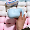 A hand holds a light blue soap ball squishy fidget toy among pink and white versions.