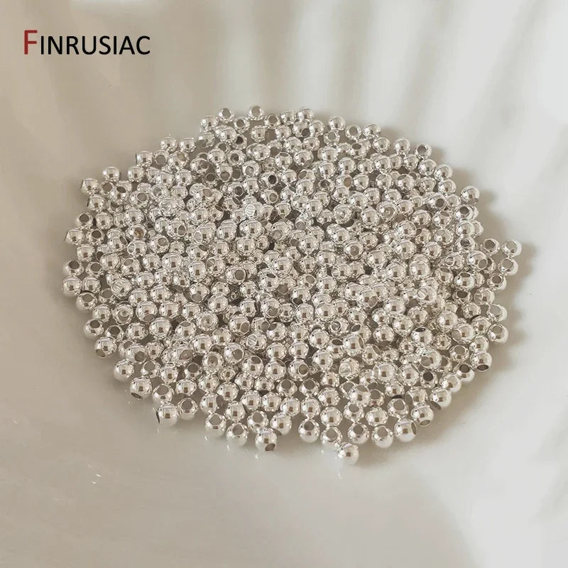 A pile of small, round, silver-colored spacer beads for jewelry making.