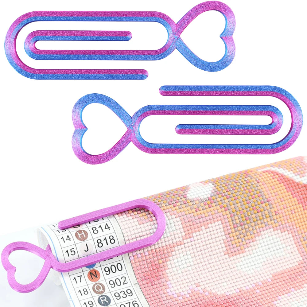 A set of two heart-shaped plastic clips in purple and blue for diamond painting canvas