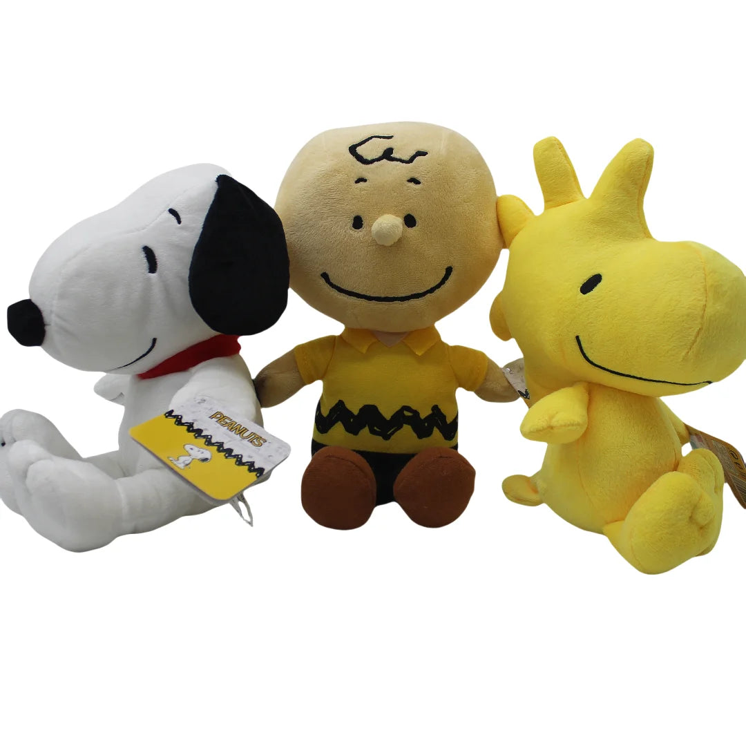 A set of three Peanuts Snoopy plush toys: a white dog, a yellow character, and a yellow-shirted character.
