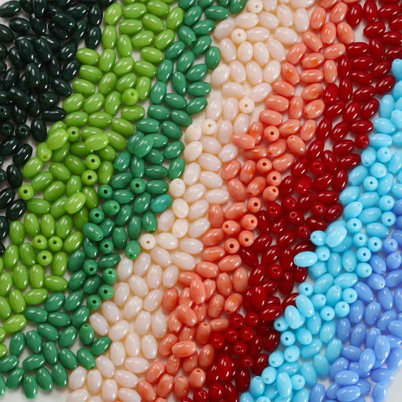 A colorful arrangement of oval glass rice grain beads in shades of green, pink, red, and blue.