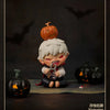 A collectible figure of a vampire with white hair and orange skin, holding a silver locket, standing in front of carved pumpk