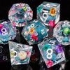 A collection of iridescent liquid core dice in various shapes and colors, including pink, blue, and clear glass.