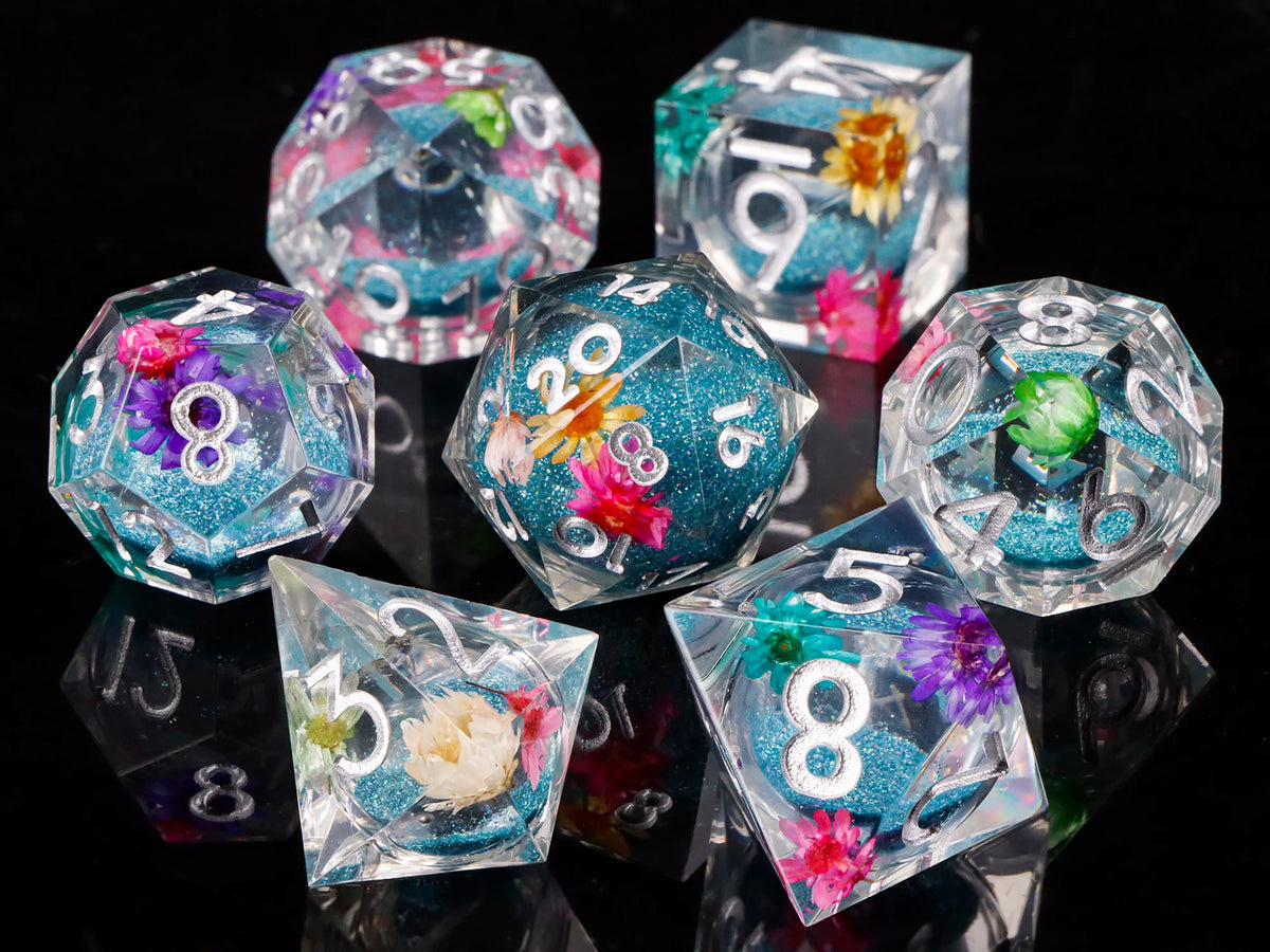 A collection of iridescent resin dice in various shapes and colors, including pink, blue, and green hues.
