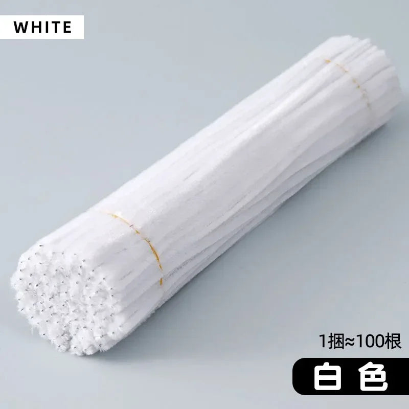 A white cylindrical roll of craft material, likely chenille stems, is shown diagonally on a light gray surface.