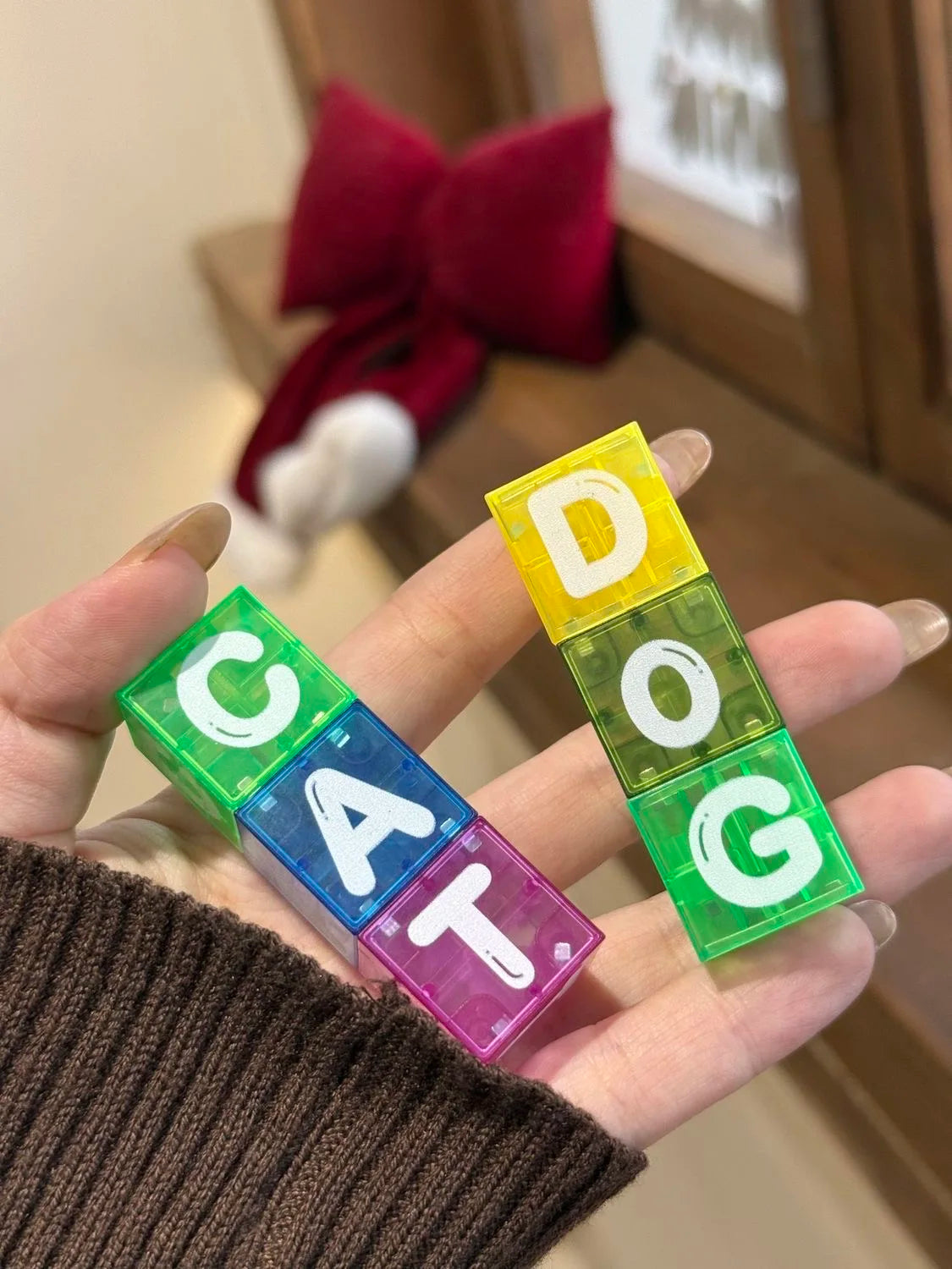 يد تمسك بمجموعة من مكعبات البناء المغناطيسية الملونة على شكل حرفي CAT و DOG.