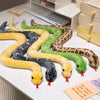 A collection of lifelike simulation snake plush toys in various colors and patterns laid out on a white surface.