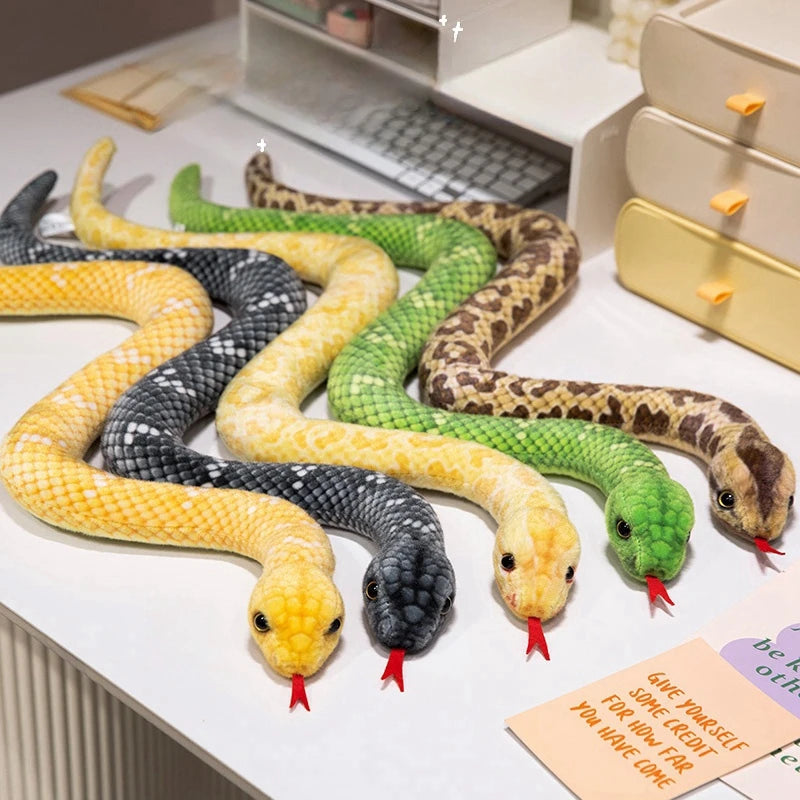 A collection of lifelike simulation snake plush toys in various colors and patterns laid out on a white surface.