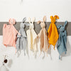A collection of soft cotton muslin baby comforters shaped like rabbits in various pastel and warm tones.