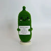 A handwoven green crochet pencil ornament shaped like a cactus with a smiling face.