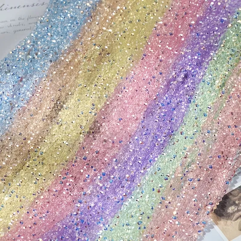 A close-up of multicolor aurora cut glass beads in various shades of pink, purple, and green arranged in stripes.