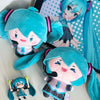 A plush keychain of an anime girl with bright blue hair and a pink outfit.