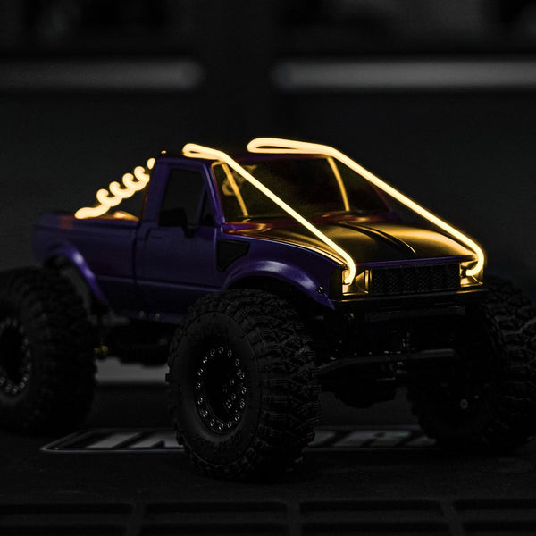A purple RC truck with yellow LED strip lights on, viewed from the front.