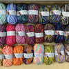 A collection of spools of soft milk cotton yarn for knitting and crochet in various colors and shades.