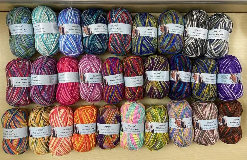 A collection of spools of soft milk cotton yarn for knitting and crochet in various colors and shades.