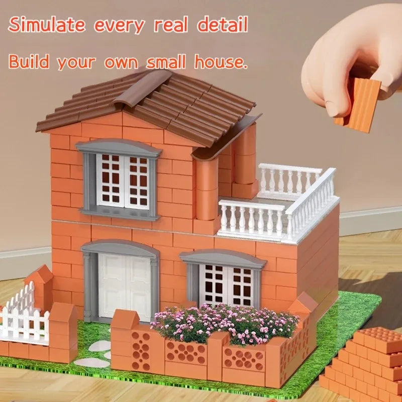 A small brick house model built from orange bricks and white trim, featuring a roof, windows, and a decorative fence.