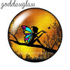 A round glass cabochon with a vibrant orange and yellow gradient background featuring a silhouette of a winged figure against