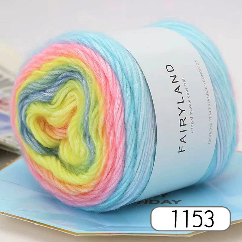 A spool of gradient rainbow yarn is shown on a light blue background.
