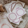 A stack of vintage scrapbook paper sheets featuring delicate pink and maroon floral borders for journaling and crafts.