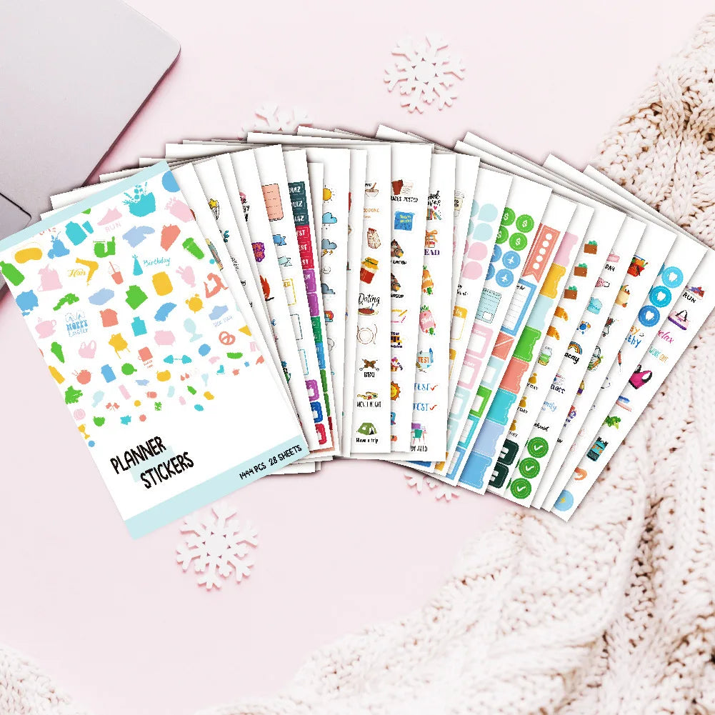 A collection of planner stickers in various colors and designs laid out on a pink surface.