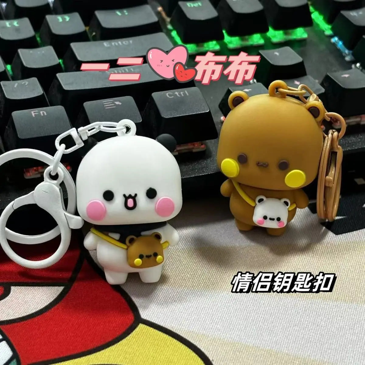 A set of cute cartoon bear keychains, featuring a white and an orange bear, displayed on a keyboard.