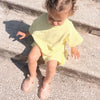 A young girl wearing yellow Gladiator jelly sandals outdoors.