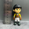 A Playful Cartoon PVC figurine of a girl with black hair and green eyes, wearing a yellow top and brown pants.