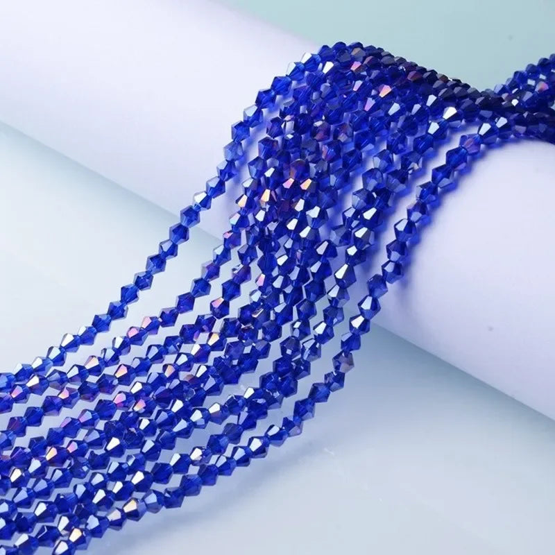 A close-up of deep blue faceted crystal beads strung together, laid out on a white surface.