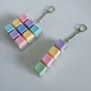 A fidget keychain stress reliever featuring colorful, square, clickable keys in pastel shades.