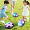 Two children playing with glowing LED hover soccer balls on a green lawn.