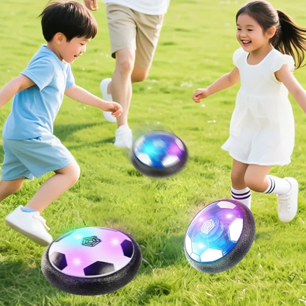 Two children playing with glowing LED hover soccer balls on a green lawn.